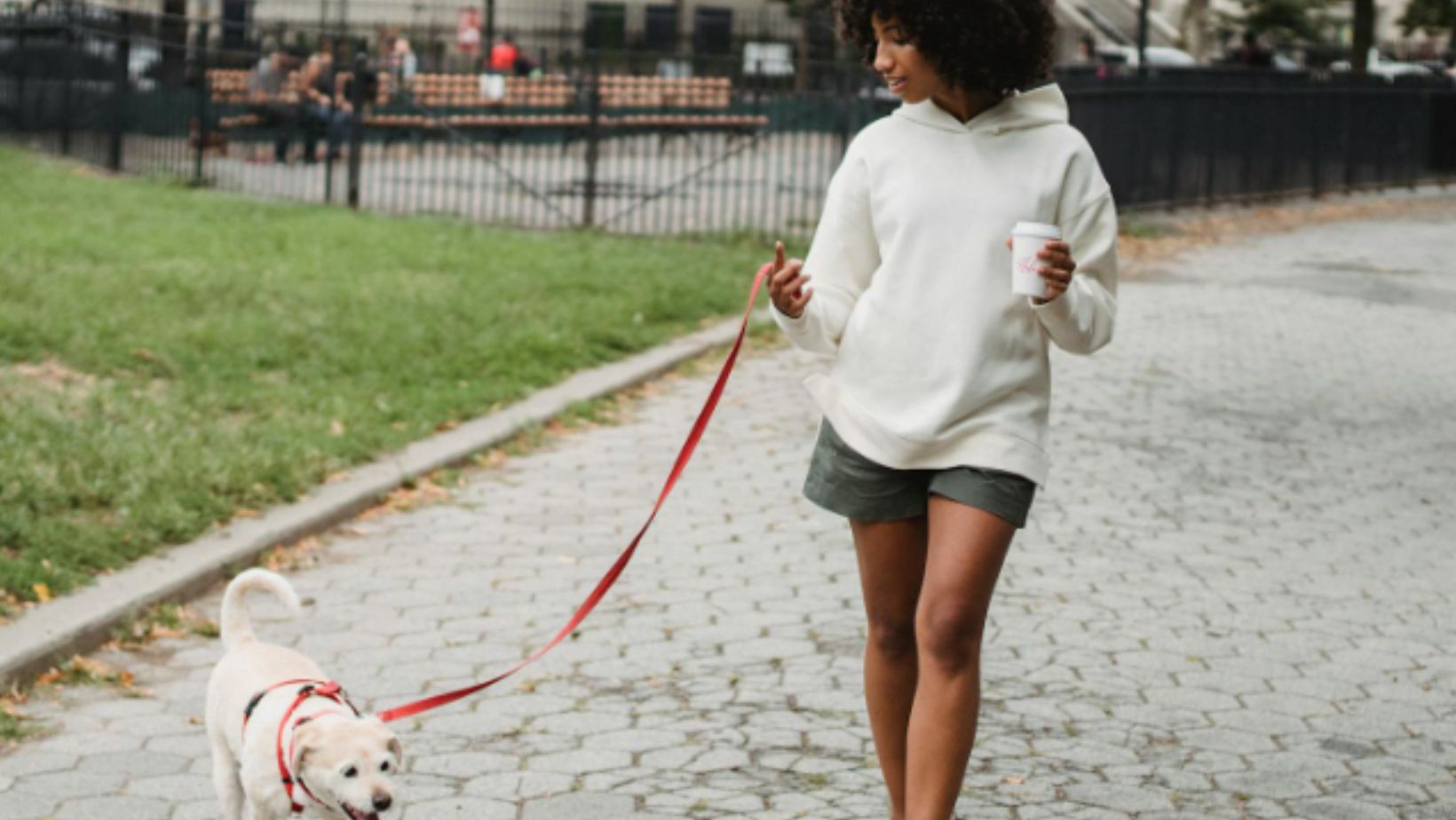 Black woman with coffee walking dog