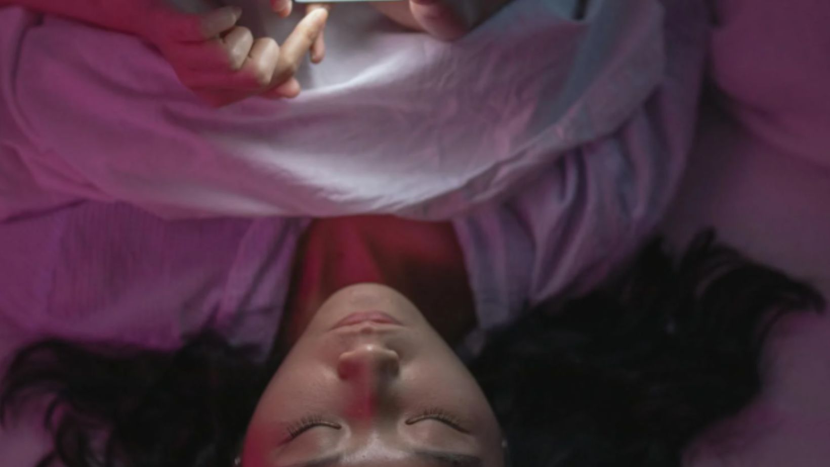 A Woman Lying on Bed and Holding an Iphone 